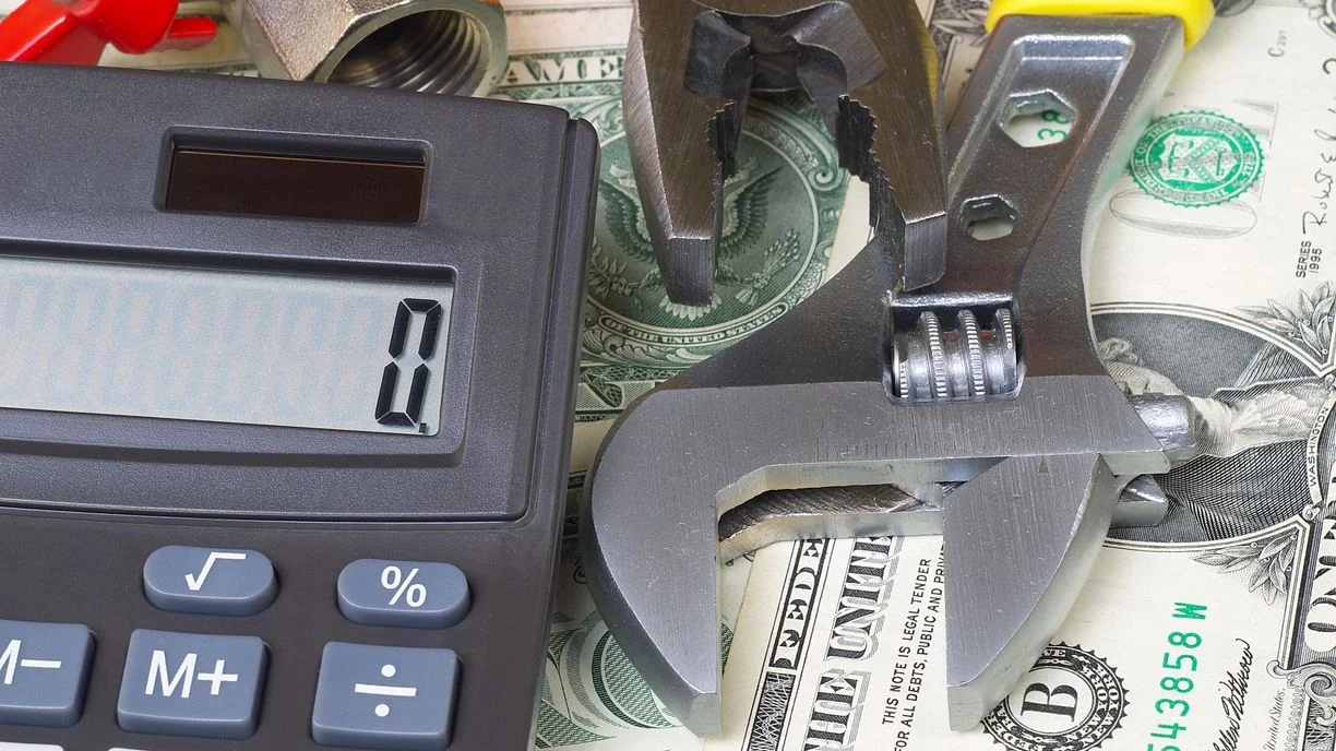 a calculator and wrench on top of money implying the calculation for appliance repair costs